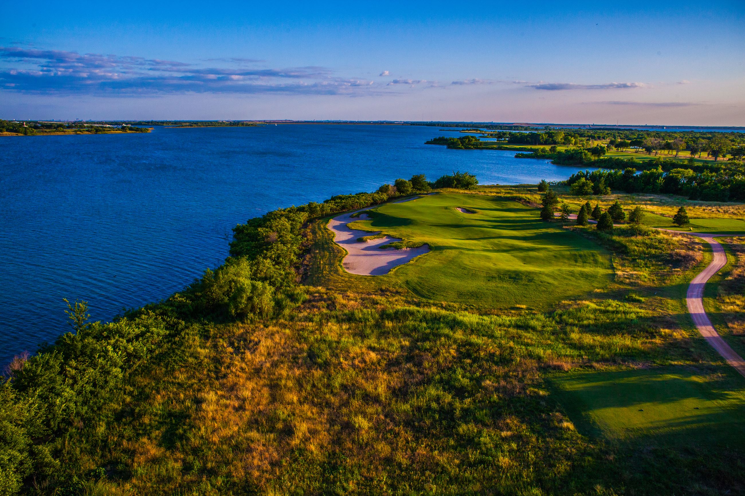 Aerial view of a golf course with sand traps beside a blue lake