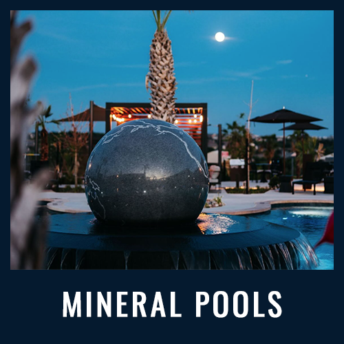 A glowing moon rises over a mineral pool with a large stone globe fountain and palm trees