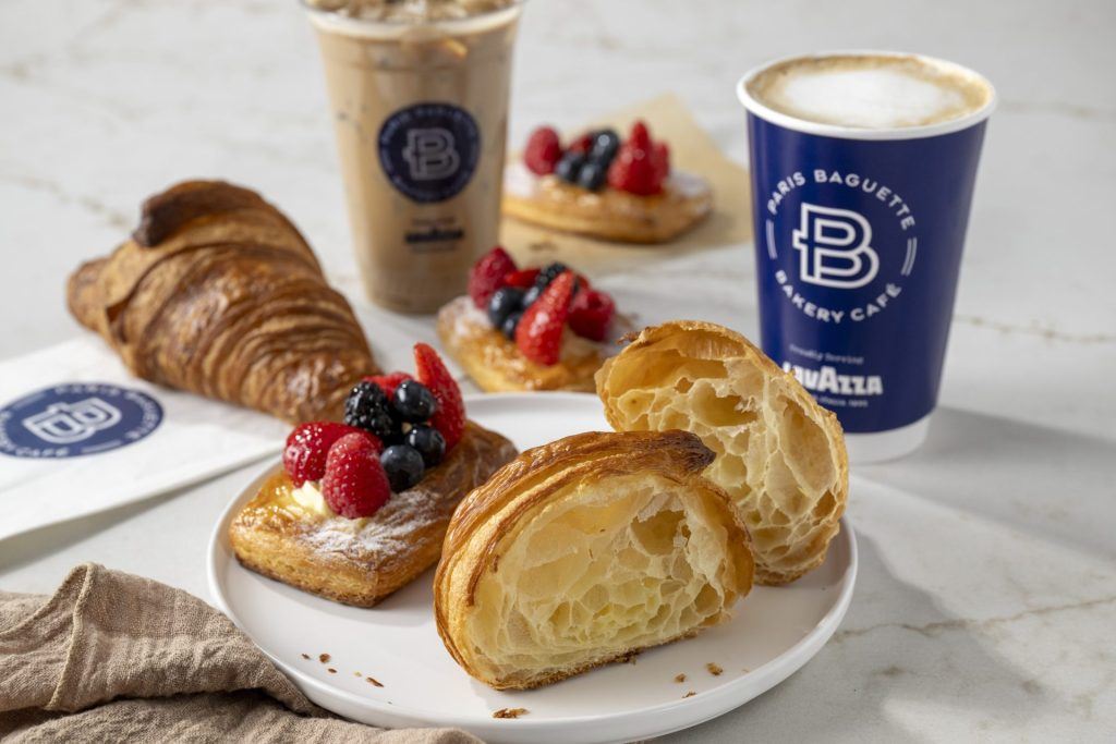 Assorted pastries and coffee from Paris Baguette Bakery Café displayed on a white marble table.