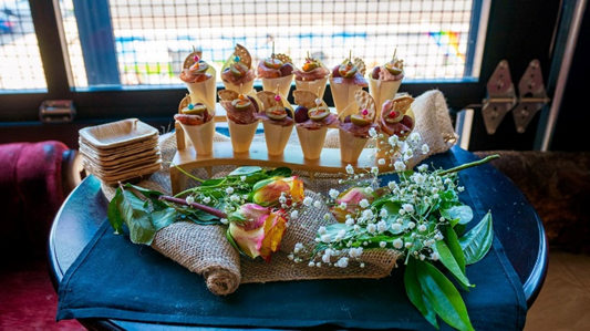 Mini dessert cones displayed with flowers on a table set for a special event or celebration.